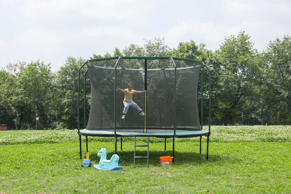 Ni&ntilde;o saltando en un trampol&iacute;n cerrado de 14 pies en un patio residencial: soluci&oacute;n de entretenimiento en el hogar